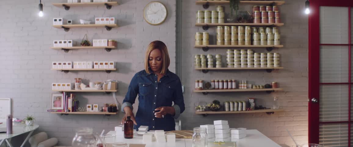 A woman in a room standing next to a table with shelves and a wall in the background