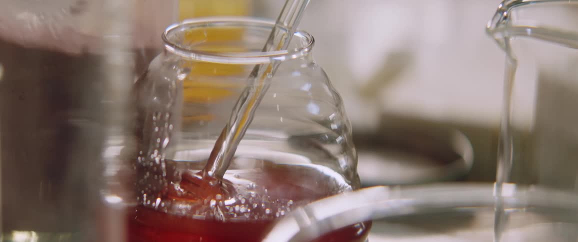 Glass spoon rests inside a glass jar containing a thick brown liquid