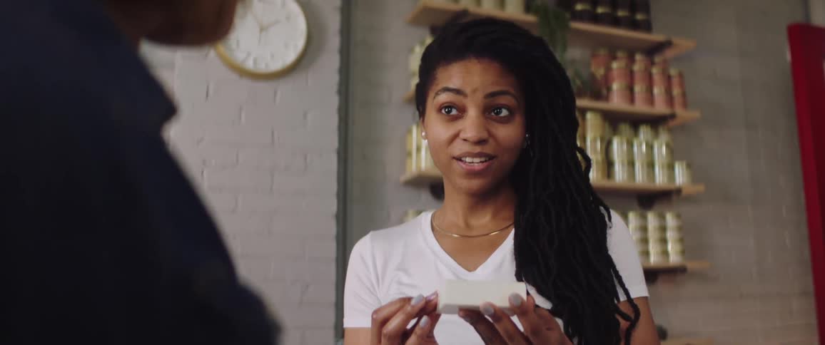 Woman smells bar of soap as she talks to store worker in store