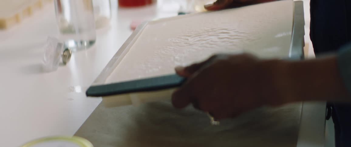 A woman in a room picking up a plastic container on a table