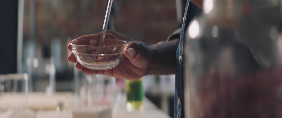 A person stirring ingredients in a glass bowl in a kitchen