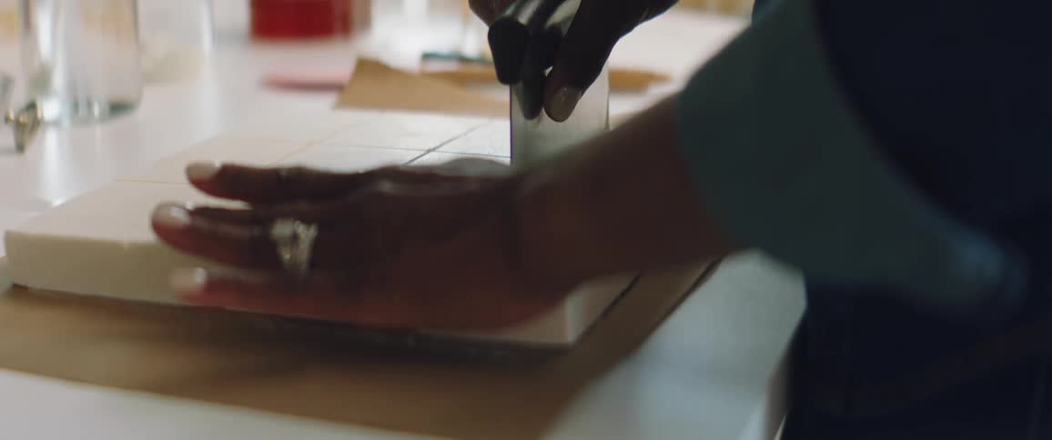 Black woman slices a batch of white fudge with a blade