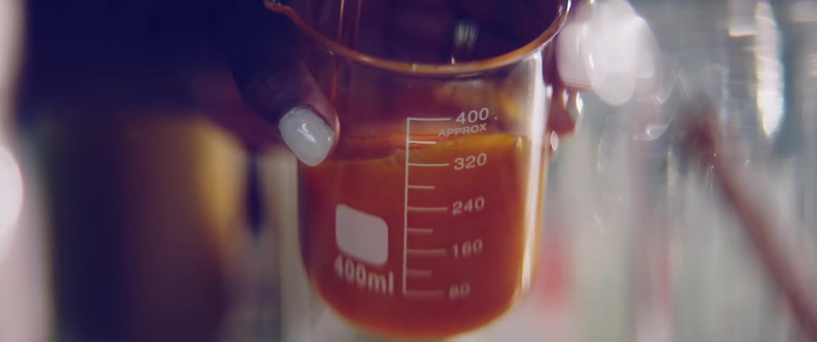 Black woman with white nail polish on her finger stirs liquid in a measuring cup