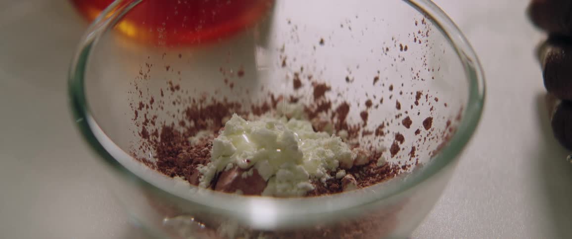 A liquid being poured into a bowl with a cream and a powder