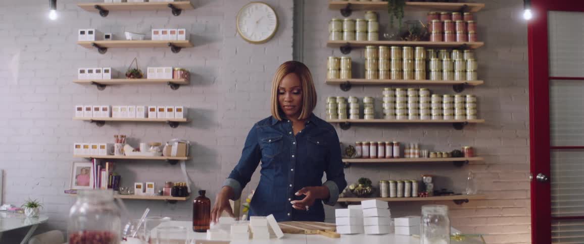 Black woman picks up a small white box and inserts it into a slightly larger white box