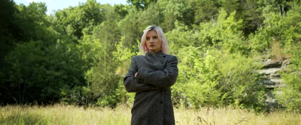A portrait of a woman standing outdoors in a forest