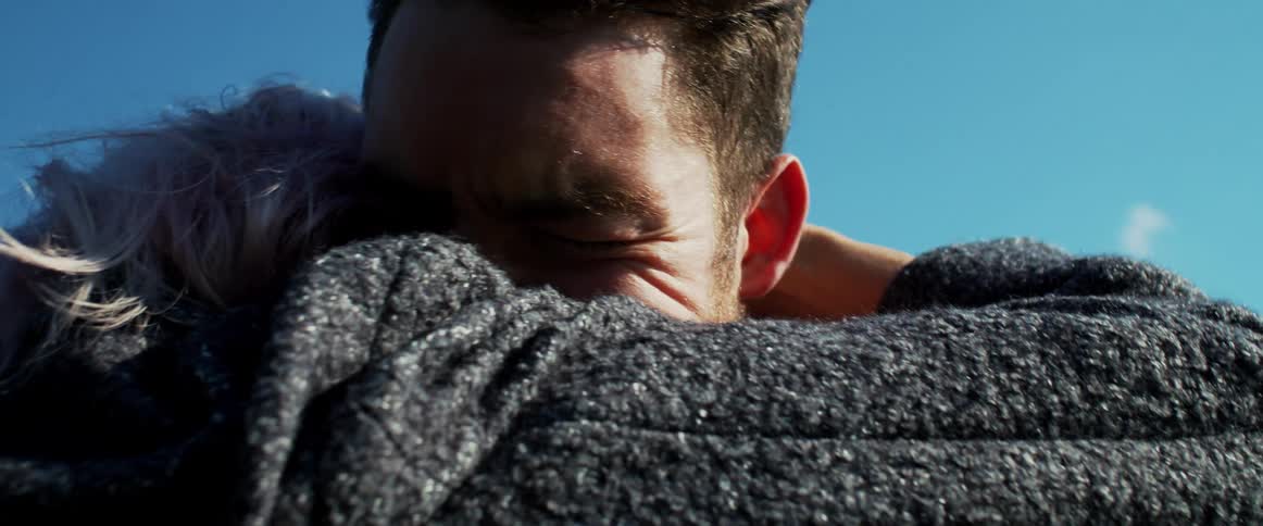 Man and woman embrace outdoors under a blue sky