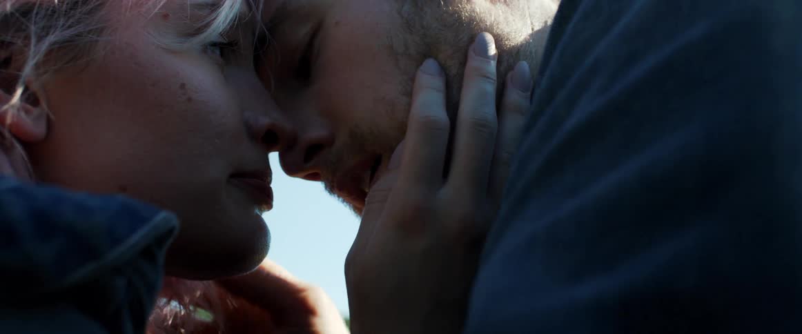 A man and a woman standing with there foreheads touching with the sky and clouds in the background