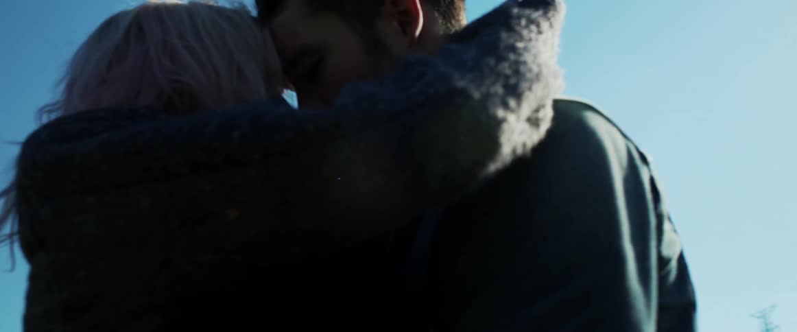 Couple cuddle and hug standing outdoors under blue sky