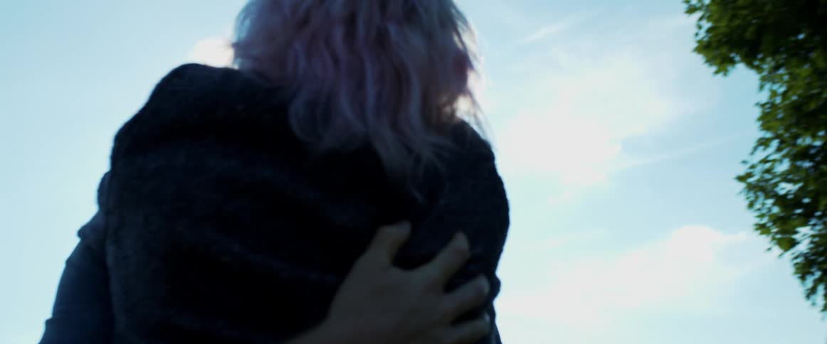 A man and woman hugging intimately outside on a sunny day
