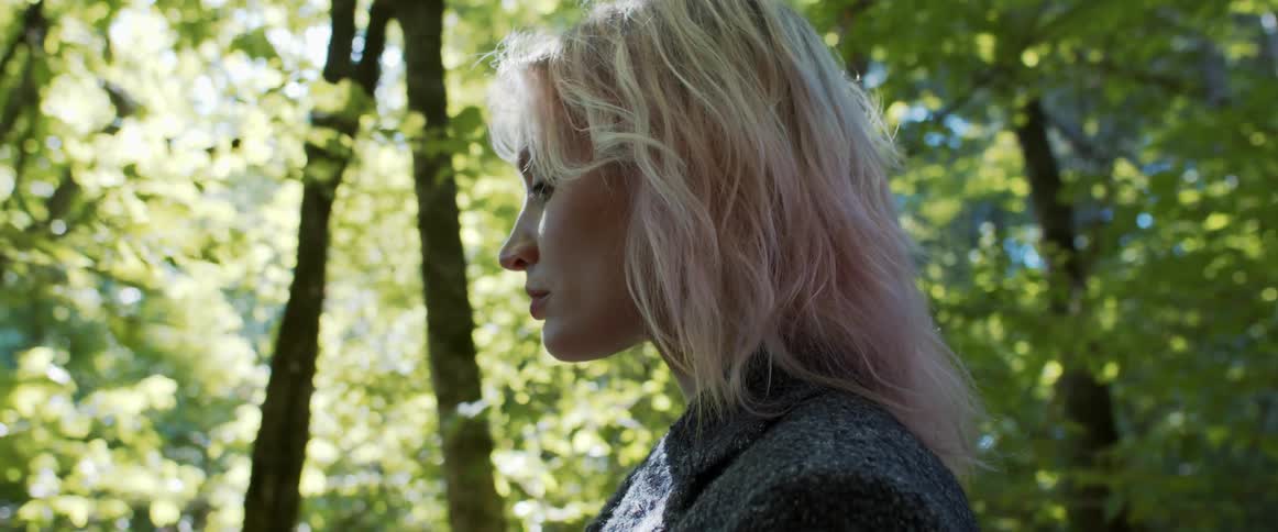 A woman walking through the forest looks around