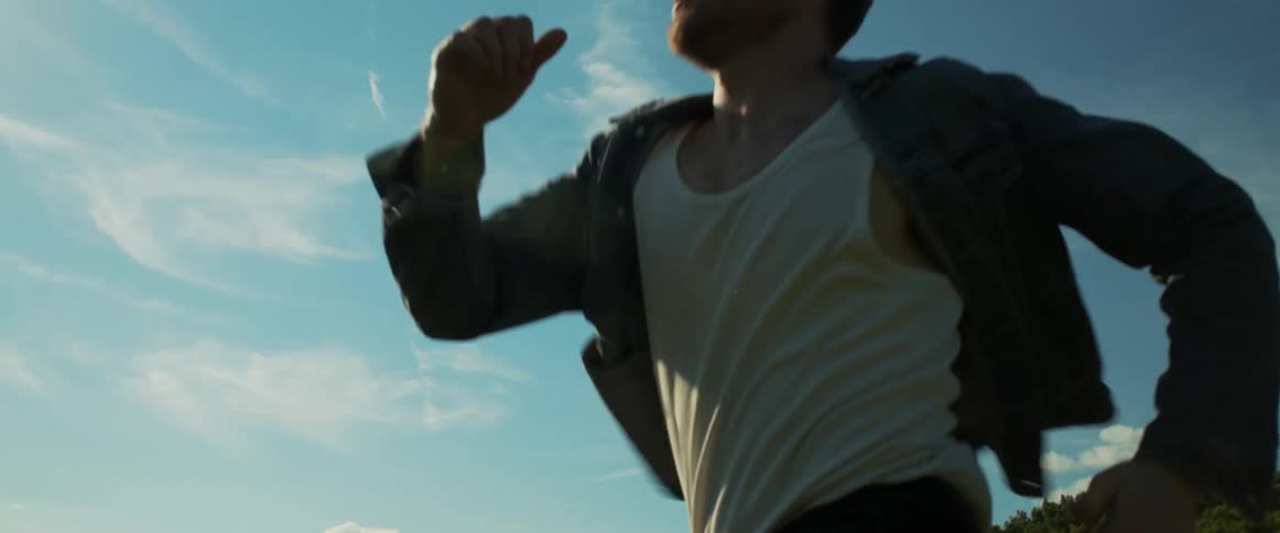 A man runs outdoors under a blue daytime sky