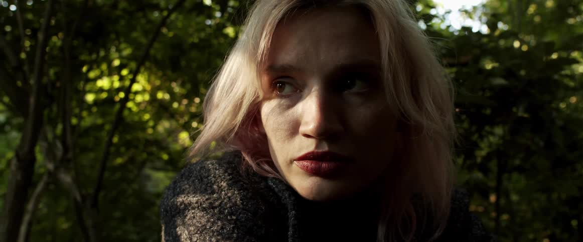 A portrait of a blonde woman outside near trees
