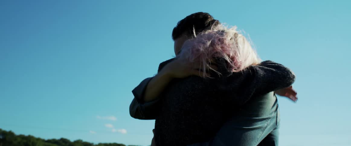 A man and woman hug each other tightly in a park