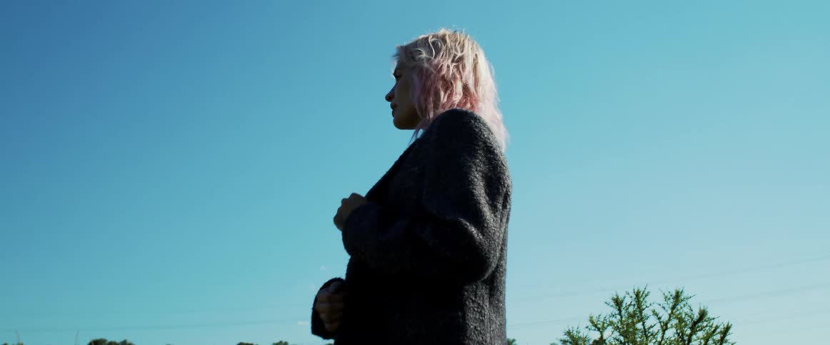 A man and a woman hugging with the sky and clouds in the background