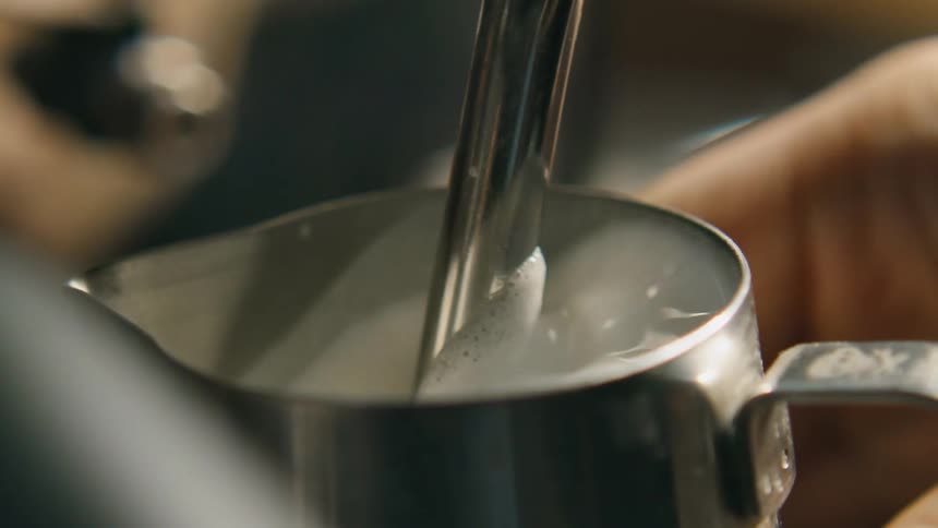 A person in a room filling up a metal container with cream
