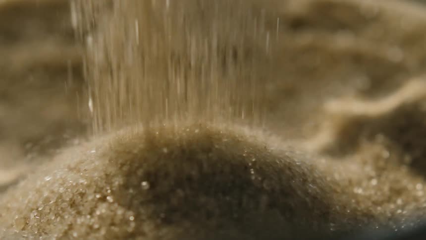 Sand pours onto a large pile of sand
