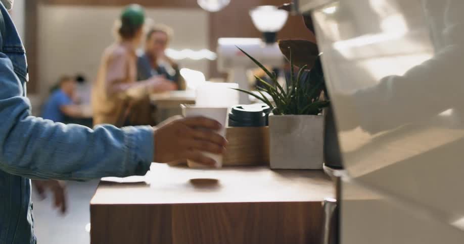 A customer taps his hands on a wood counter while waiting for his coffee