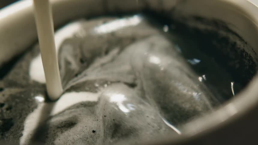 Thick milk is poured into a cup of matcha