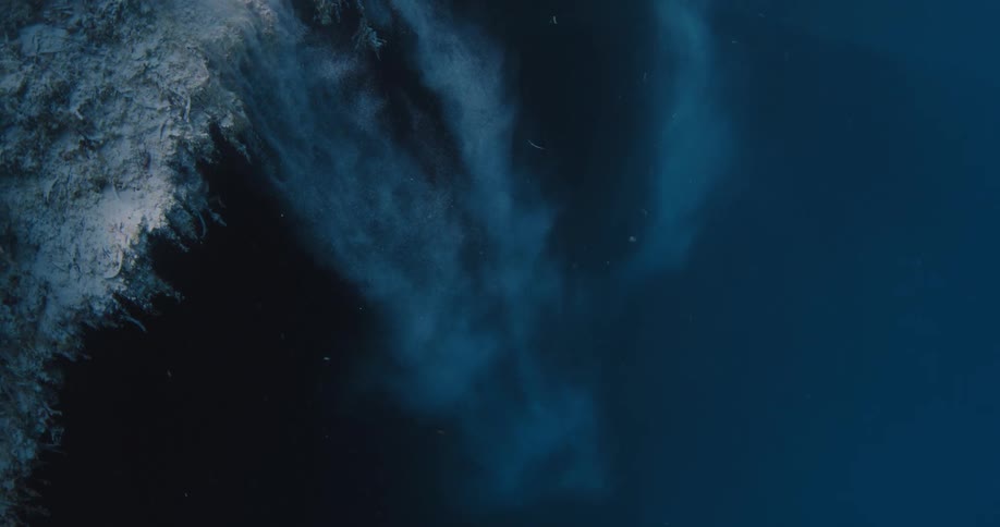 Sediment falls like sand down the side of coral reef underwater