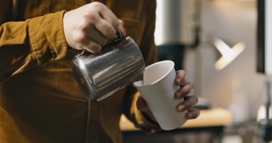 Person pouring milk in cup