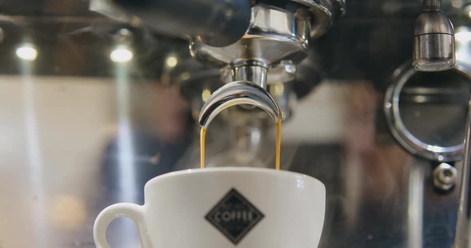 An espresso machine with steam pouring espresso into a cup in a room