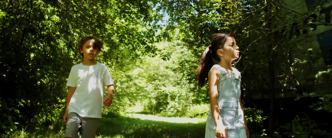 Young boy and girl walk on a path in the forest on a sunny day