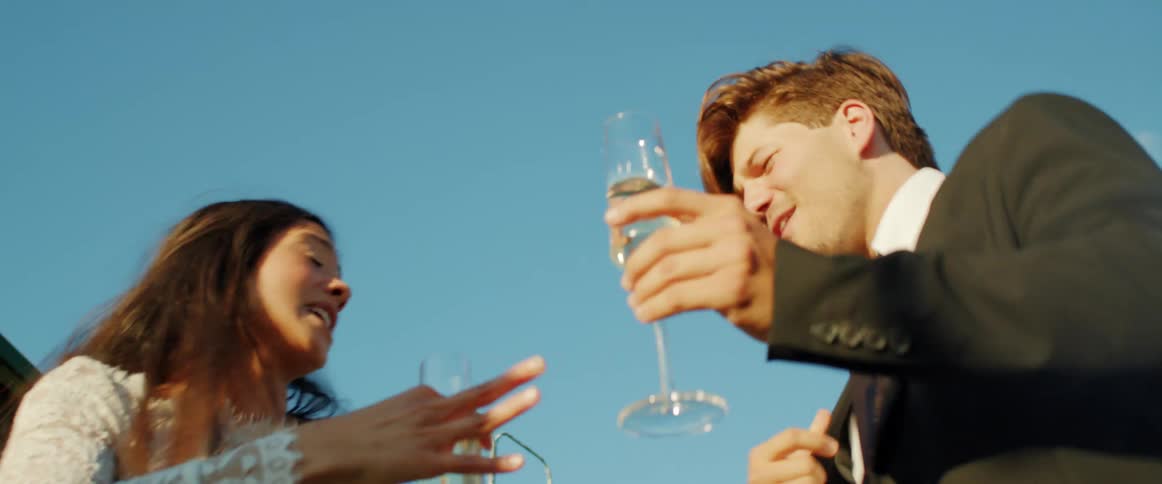 Friends holding champagne glasses dancing and singing in an outdoors party