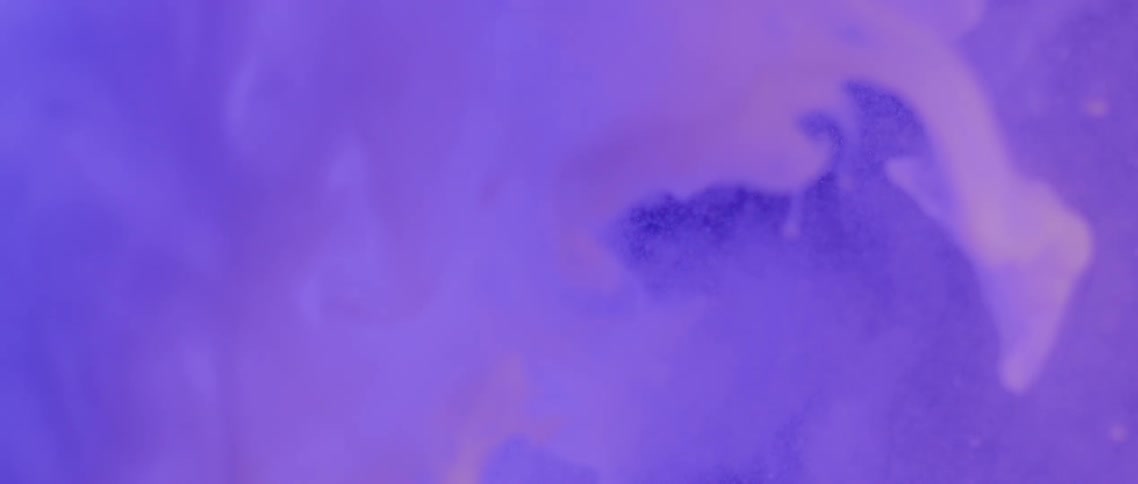 Swirls of white ink floating in water under changing purple lights