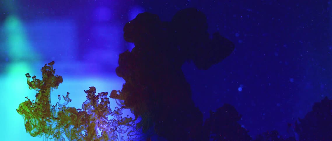 A green liquid flows upwards and mixes with a blueish fluid