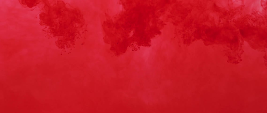 A red liquid gradually mixes and spreads as its poured into another liquid