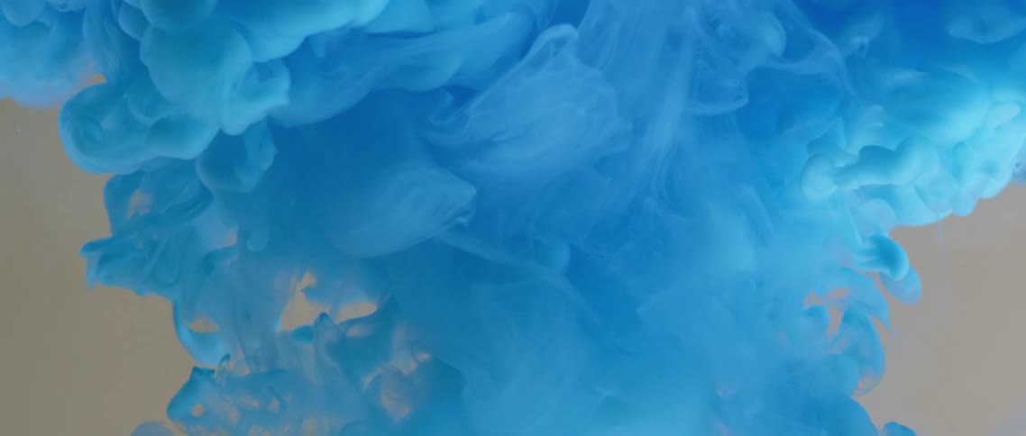 Blue clouds of powder dye burst upwards before floating and falling