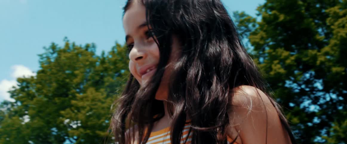Boy and girl stare at each other and smile under a blue sky