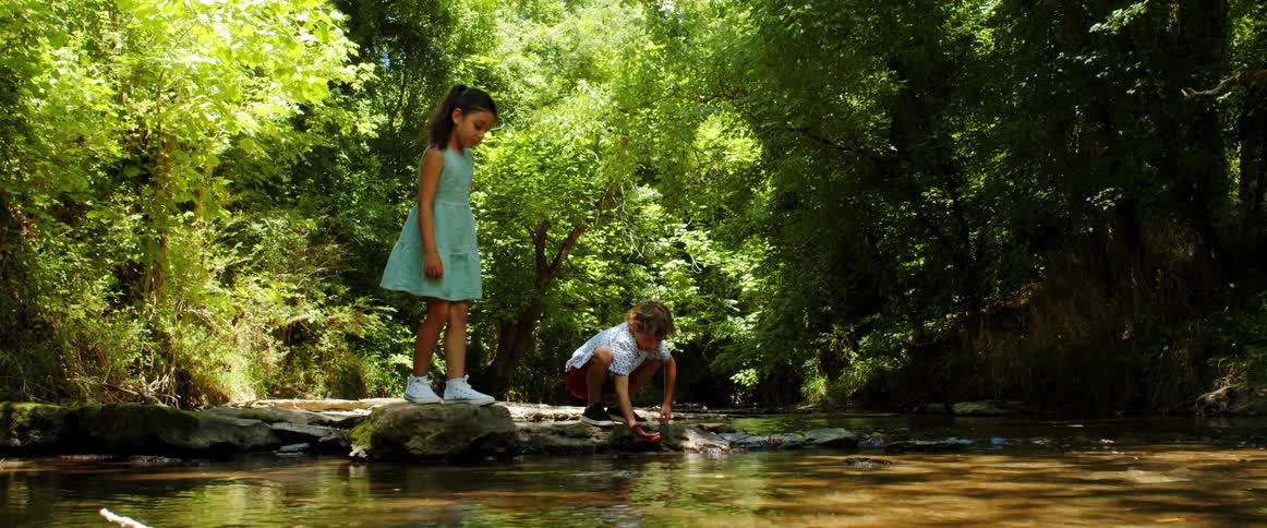 Young boy and girl play by the stream in the forest