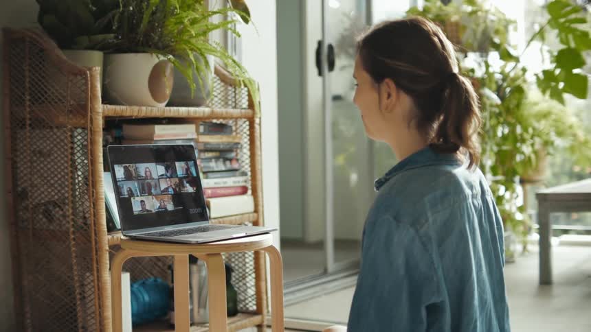 Woman talking to a group of friends on a video call through a laptop at home