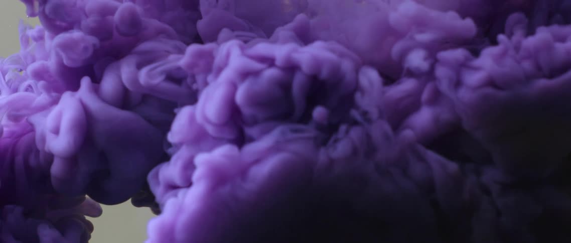 Bright waves of purple ink floating down a tank of clear water