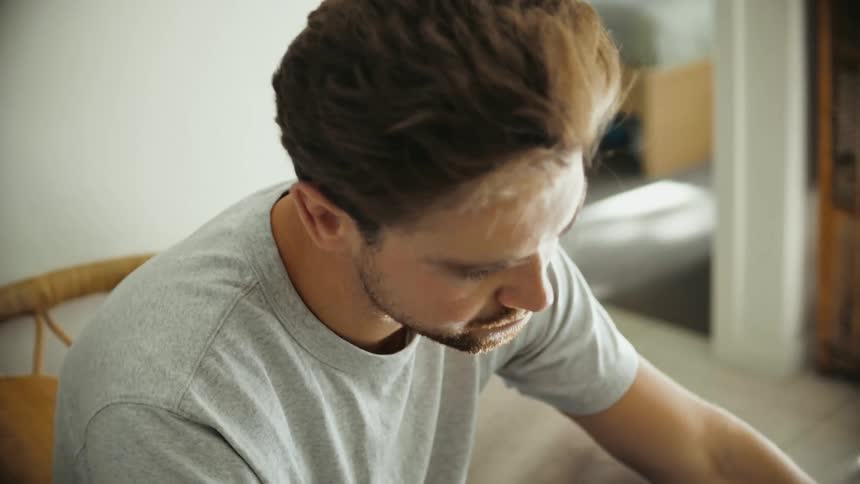 A man looking at a smartphone while sitting on an indoors chair