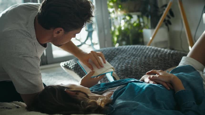 Husband reading a book points out something in the book to his wife