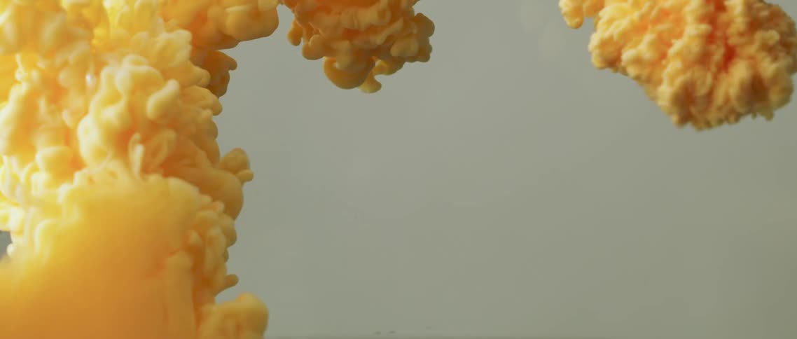 Yellow orange dye bursts and expands in clear liquid