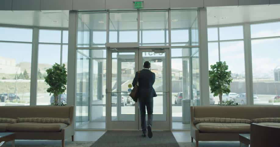 Businessman wearing a suit stops to check his cell phone before exiting an office building
