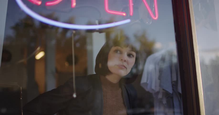 Woman pulls on a chain to illuminate a sign inside a store