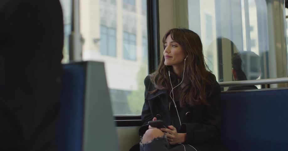 Woman uses earbuds while traveling on a bus