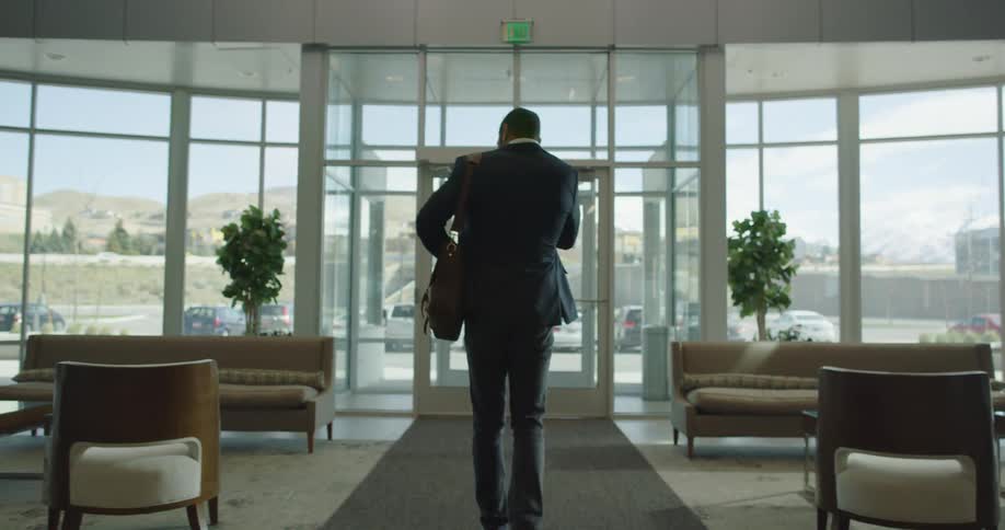 A man walks through a building lobby and checks his phone