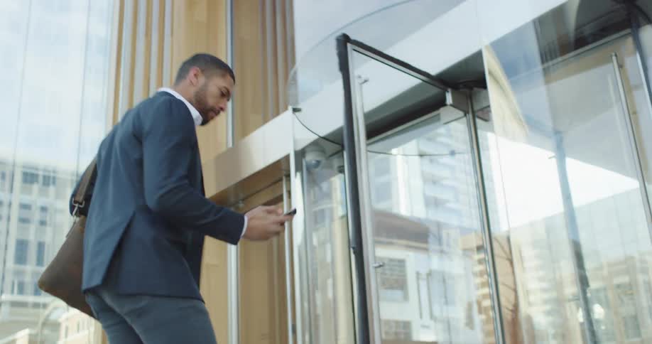 A black man walks to an office building door