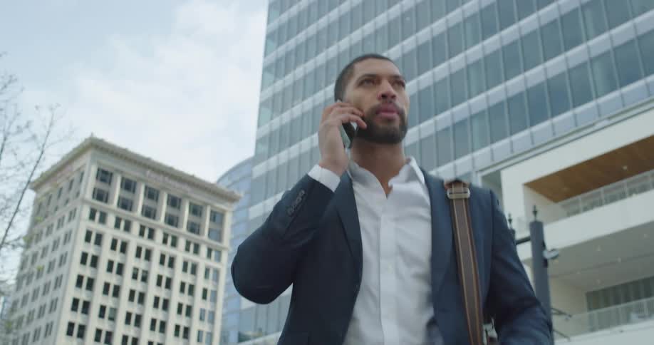 A man is walking is talking on his phone as he walks in the city