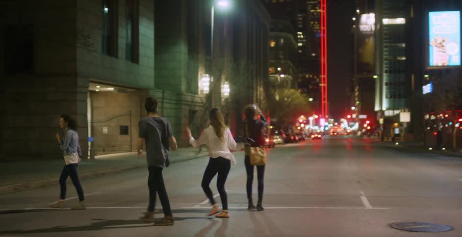 Pedestrians cross a city street at night