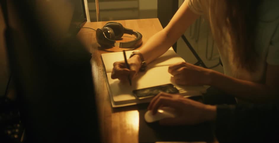 Two people sit while the woman sketches in a notebook