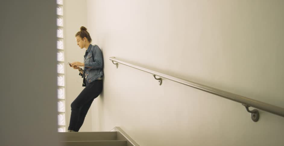 Person standing in a stairway putting earphones in their ear