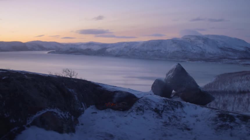 The campfire is burning out near the lake