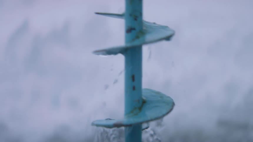 A metal tool being pulled from frozen lake water